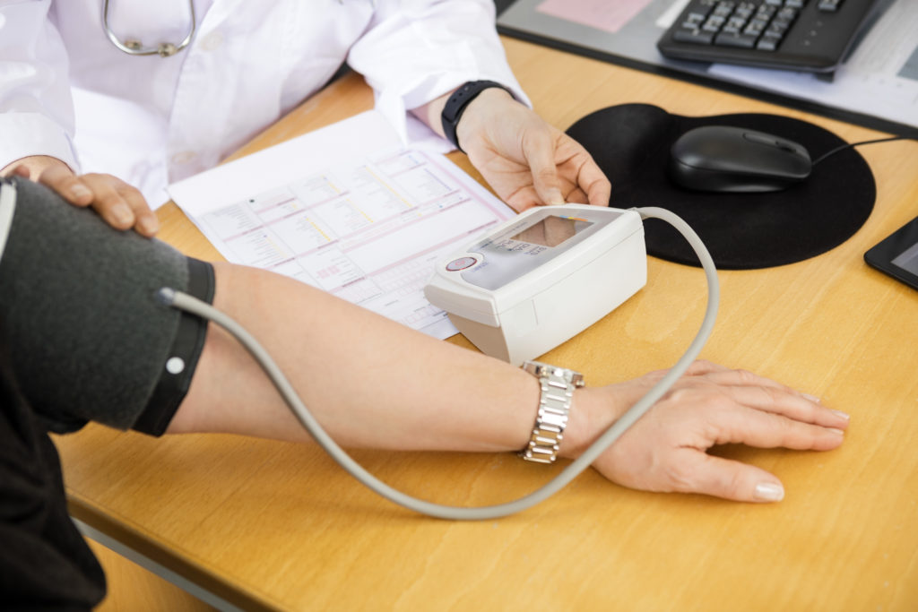 Cropped image of female doctor examining patient's blood pressure in clinic